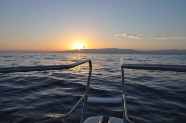 Ship railing in the middle of the sea with a beautiful horizon and the sunset