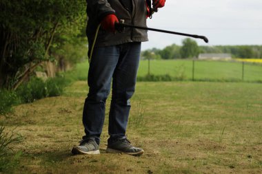 Sırt çantalı bir adam bahçedeki bitkileri ilaçlıyor..