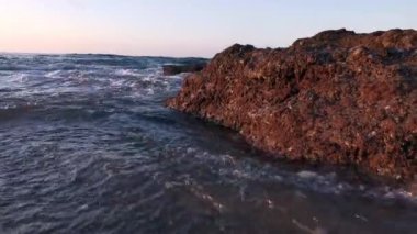 Getxo 'daki Azkorri plajından yaz gün batımı. Dalgalar kayalara çarpıyor. Sakin, sakin...