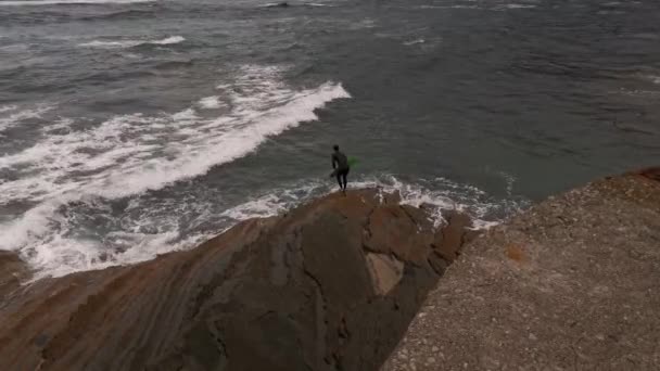 穿着湿衣 船板和鱼鳍的冲浪者 在岩石边走进水中 — 图库视频影像
