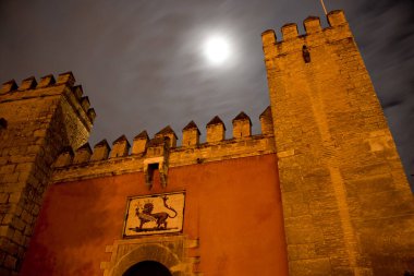Gece vakti bulutlu gökyüzü ve dolunay ile Sevilla, Endülüs, İspanya 'daki Berberi kalesinin ön kapısı.