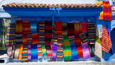 Fas tekstil dükkanında yığılmış halı, atkı ve battaniye.