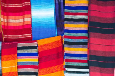 Fas tekstil dükkanında yığılmış halı, atkı ve battaniye.