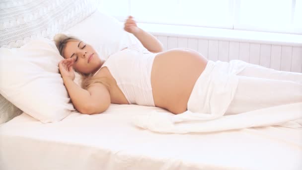 Беременная женщина просыпается утром, улыбается и смотрит в камеру — стоковое видео
