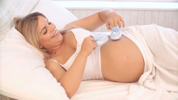 Беременная женщина играет с детскими попками на животе — стоковое видео