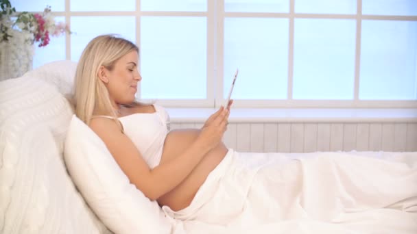 Schwangere entspannt sich mit Tablette im Bett — Stockvideo