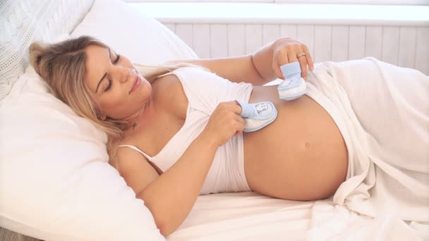 Femme enceinte jouant avec des chaussons de bébé sur le ventre — Video