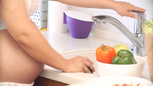 Mujer embarazada lavando pimientos en la cocina. verduras para ensalada — Vídeos de Stock