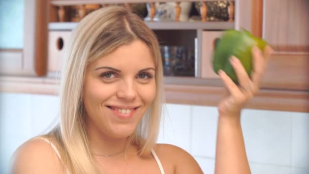 Blonde vrouw met een peper in de keuken — Stockvideo