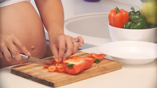 Mulher grávida corta pimenta na cozinha. legumes para salada — Vídeo de Stock