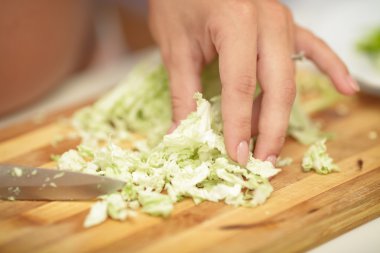 pregnant woman cuts cabbage on wooden Board, close-up clipart