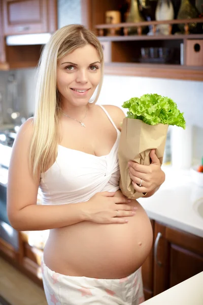 Mujer embarazada sosteniendo bolsa de papel con ensalada de hojas — Foto de Stock