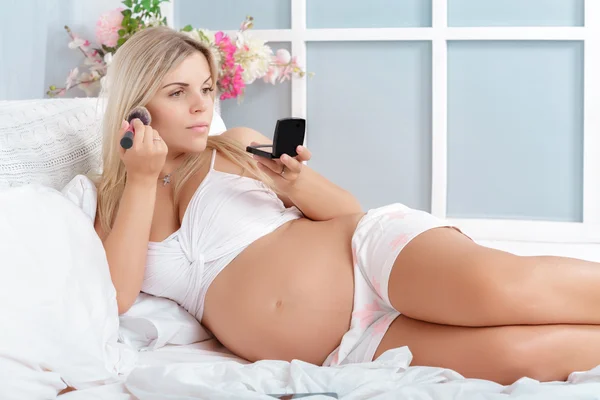 Embarazada rubia haciendo su maquillaje — Foto de Stock
