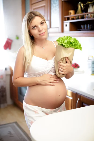 Těhotná žena držící papírový sáček s listy salátu — Stock fotografie
