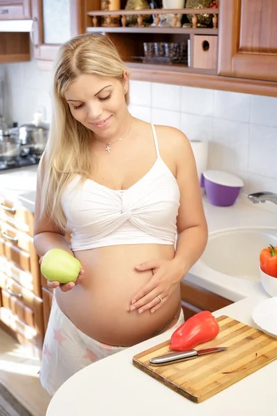 Těhotná žena držící zelené jablko a usmívá se — Stock fotografie