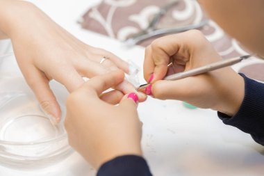 Manikürcü profesyonel manikür aracı kullanır.