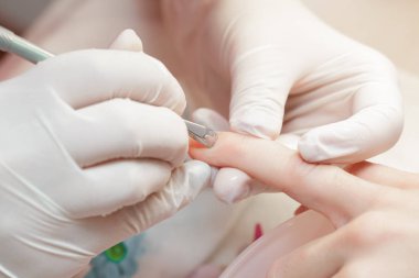 Manikürcü profesyonel manikür aracı kullanır.