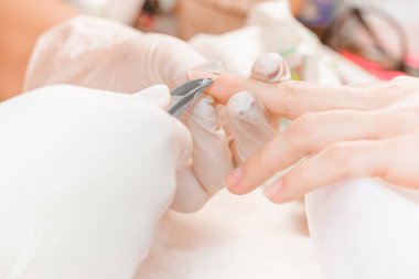 Manikürcü profesyonel manikür aracı kullanır.