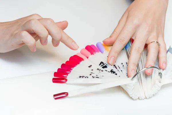 Menina escolhe a cor do polonês da manicura . — Fotografia de Stock