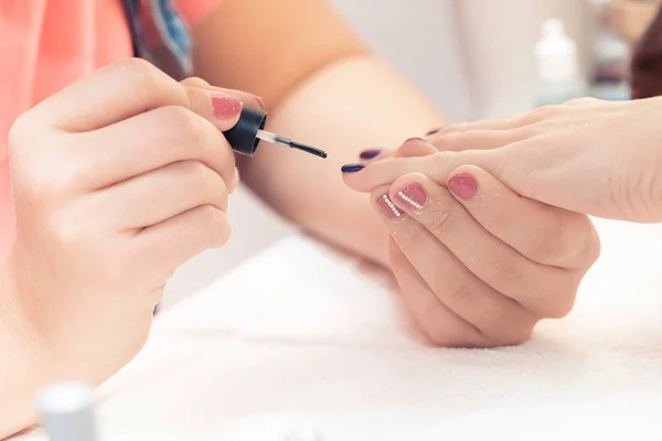beautician applying Polish nails to women