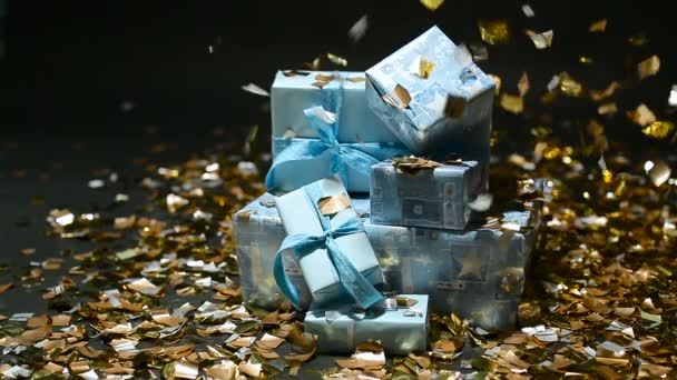 Confettis d'or tombant sur des boîtes cadeaux bleues — Video