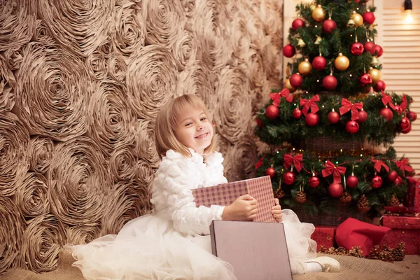 Маленька усміхнена дівчинка відкриває чарівну різдвяну подарункову коробку — стокове фото