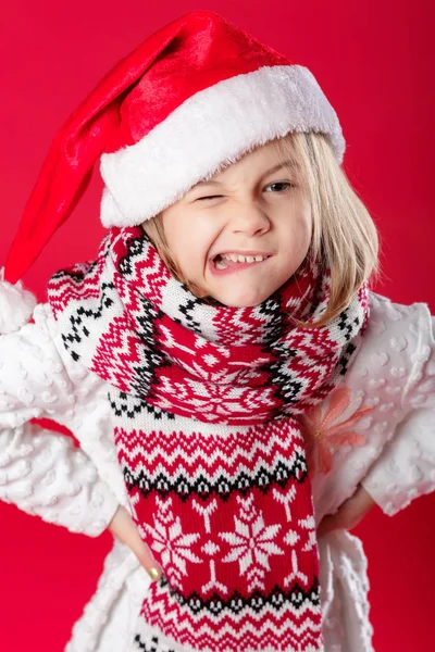 Little girl in santa hat and scarf on red background — Stock Photo, Image
