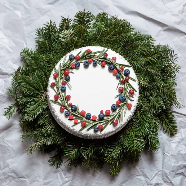 Christmas cake with berries on the background of fir branches — Stock Photo, Image