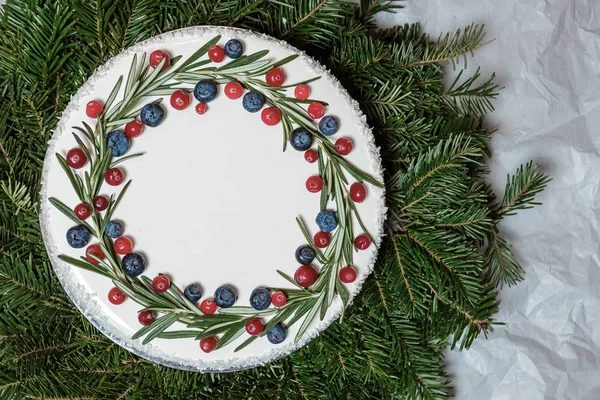 Рождественский торт с ягодами на фоне еловых ветвей — стоковое фото