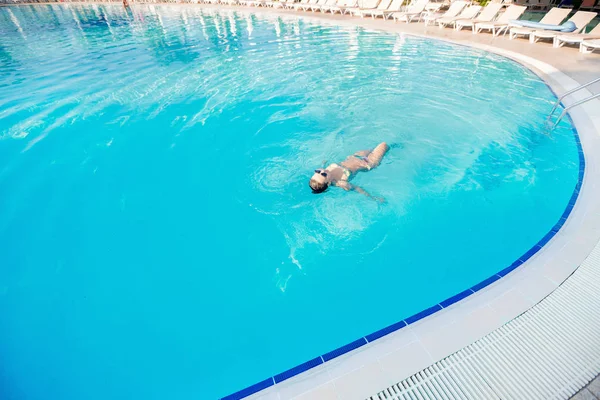 Mujer nadando en una piscina de agua azul — Foto de Stock