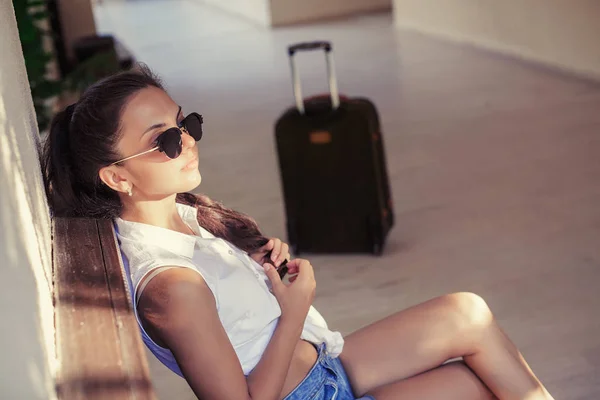 Mujer con una maleta se sienta y espera — Foto de Stock