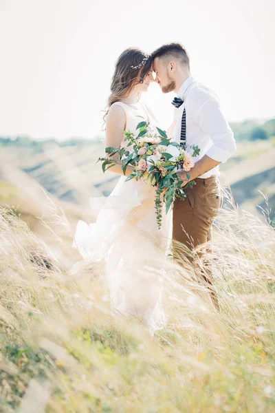 Braut und Bräutigam umarmen sich bei der Hochzeit in der Natur. — Stockfoto