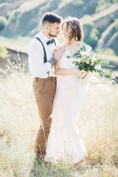 Braut und Bräutigam umarmen sich bei der Hochzeit in der Natur. — Stockfoto