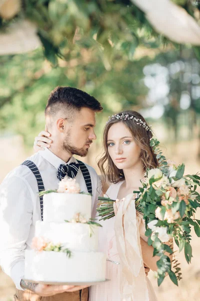 Nevěsta a ženich drží svatební dort — Stock fotografie