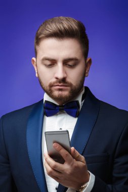 Smokin ve papyon telefonda konuşurken başarılı adam. Smartphone, mavi arka plan tutan işadamı