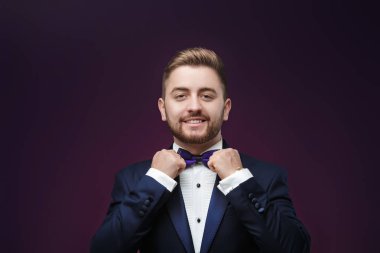 Yakışıklı adam smokin ve papyon kameraya bakıyor. Moda, Festival giyim. koyu arka plan üzerinde emcee