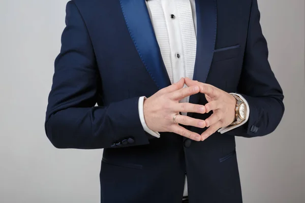 Händerna på ung framgångsrik affärsman i smoking och grå bakgrund. brudgummen på bröllop — Stockfoto