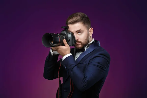 Fotógrafo profissional de sucesso em smoking usar câmera digital DSLR no fundo escuro — Fotografia de Stock