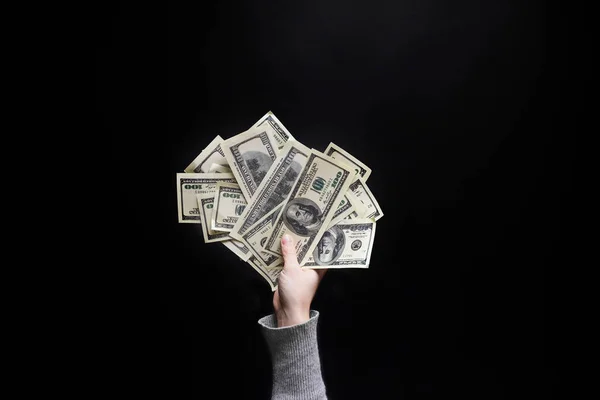 Mano femenina sosteniendo un billete de cien dólares sobre fondo negro. c) — Foto de Stock