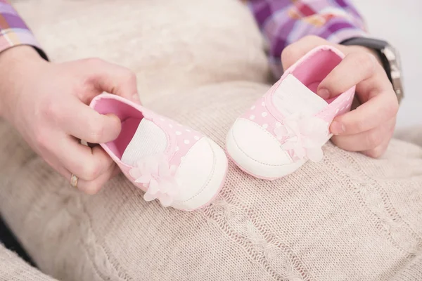 Ροζ μποτάκια για νεογέννητο μωρό στα χέρια του μπαμπά. εγκυμοσύνη — Φωτογραφία Αρχείου