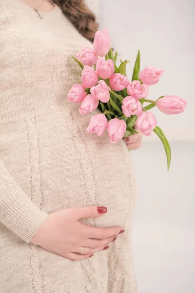 Těhotná žena s kyticí tulipánů touch bell. Detailní záběr — Stock fotografie