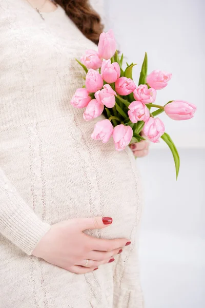 Těhotná žena s kyticí tulipánů touch bell. Detailní záběr — Stock fotografie