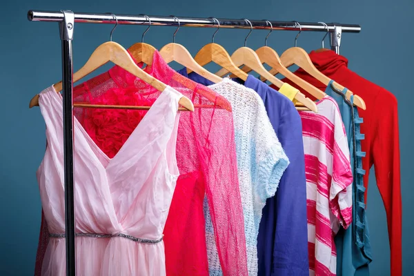 Colorful womens clothes on wood hangers on rack on blue backgrou — Stock Photo, Image