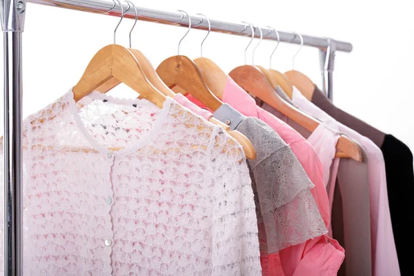 Gray, pink womens clothes on hangers on rack on white background — Stock Photo, Image