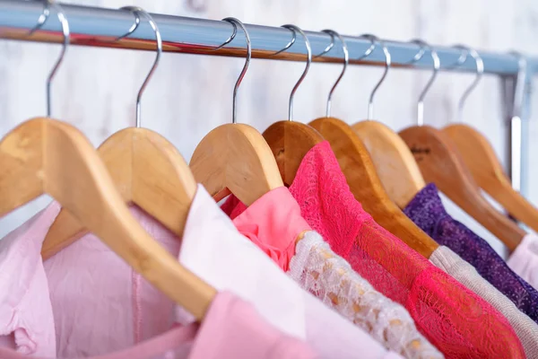 pink womens clothes on hangers on rack in fashion store. closet