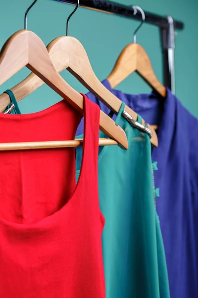 Kleurrijke womens shirts op houten hangers op blauwe achtergrond. RGB — Stockfoto