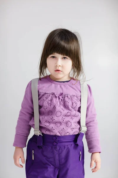 Niña linda en ropa púrpura sobre fondo gris —  Fotos de Stock