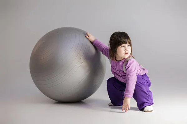 Büyük top Fitness gri mor giysili küçük kızı — Stok fotoğraf
