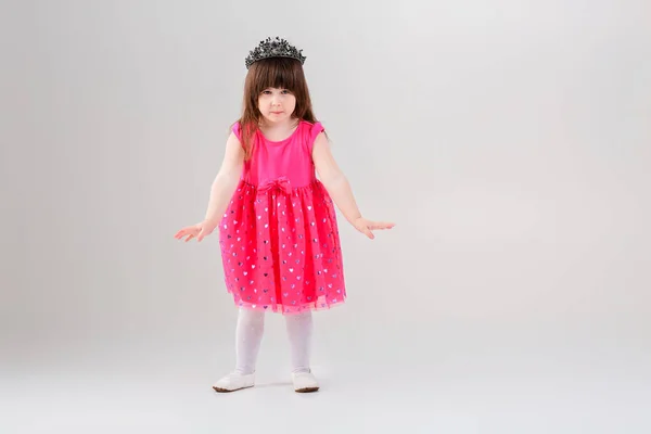 Hermosa niña en vestido de princesa rosa con corona tratando de t —  Fotos de Stock