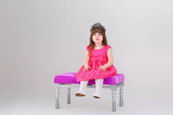 Pembe prenses güzel küçük kız elbise ile oturmuş taç — Stok fotoğraf